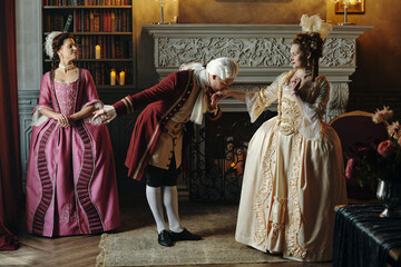 Caucasian middle aged man wearing Baroque period costume bowing and kissing hand of Caucasian...