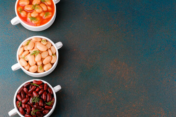 Three bean types in white bowls top view on dark surface for protein-rich, vegan or food variety concept