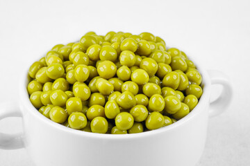 Green peas in white bowl  on bright background for clean eating, vegan food or healthy side dish concept