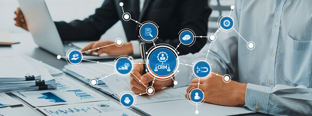 Business professionals collaborate in a modern office, using digital CRM solutions to analyze data...