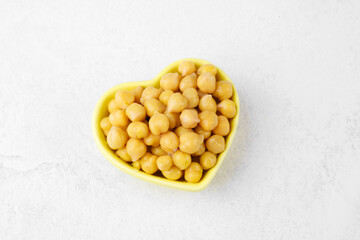 Heart shaped bowl of chickpeas on white background for love food, healthy vegan lifestyle or plantbased nutrition concept