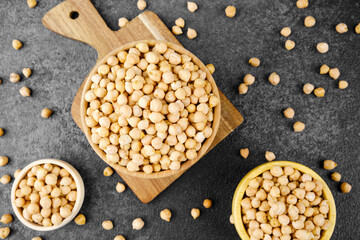 Top view of bowls filled with chickpeas on black background for food layout, nutrition or healthy...