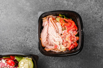 Mixed salad bowls with avocado, cherry tomatoes, blue cheese and turkey in black bowls for healthy lunch or food variety concept