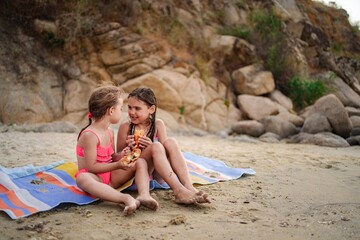 Sisterly joy at sunset on the beach while sharing snacks