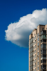 Modern apartment building with large windows under a blue sky and fluffy white clouds. Urban...