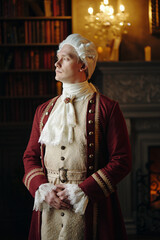Caucasian middle aged man wearing Baroque period costume standing with hands clasped in ornate...