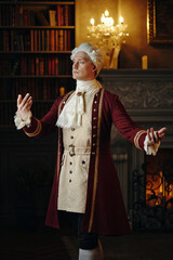 Caucasian middle aged man wearing historical Baroque costume standing with arms raised in elegant...