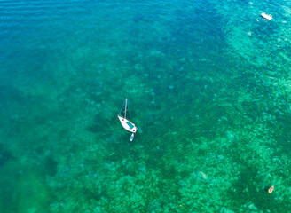 Aerial top down view of white sail boats docked in a crescent shape in a turquoise water harbor at Yvoire France 