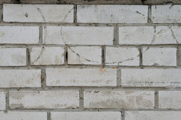 Close up view of a light gray brick wall, showing the texture and pattern of the bricks and mortar. The image is well lit, displaying subtle variations in the shade of the bricks