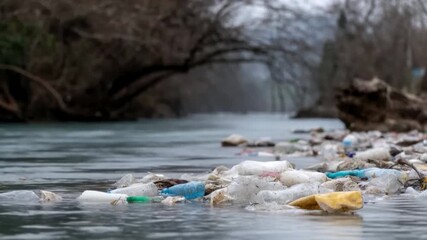 A polluted riverbank littered with plastic waste highlights environmental challenges, emphasizing conservation and waste management strategies Overcast sky adds a somber tone