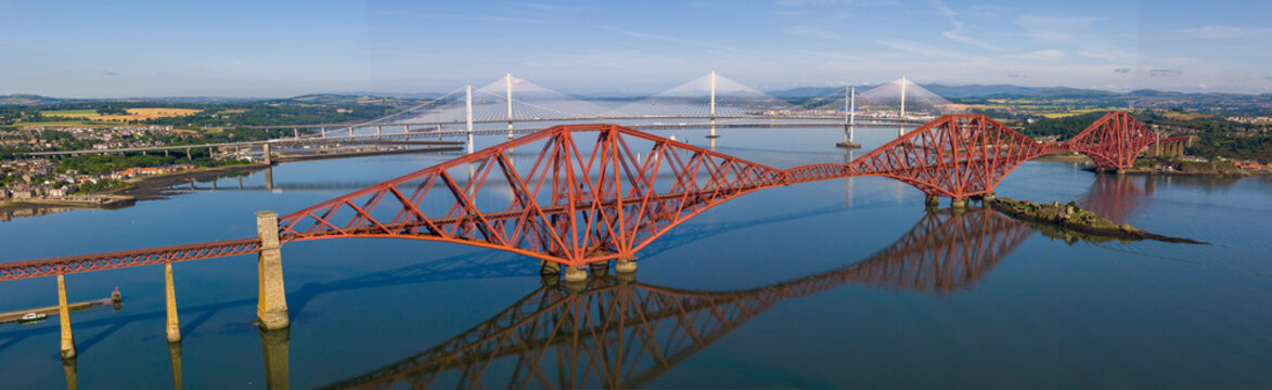 Panoramic aerial image featuring the Forth bridge with the Forth Road Bridge and Queensferry crossing Bridge on the background. Edinburgh - Scotland. 
