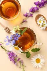 Aromatic herbal tea in glass cups, different flowers and mint on beige background, flat lay
