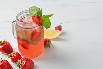 Refreshing drink with strawberries, ice and mint on white table, closeup. Space for text