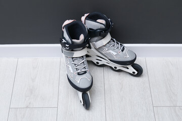 Pair of roller skates on floor near black wall
