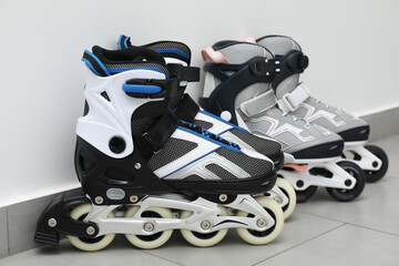 Pairs of roller skates on floor near white wall