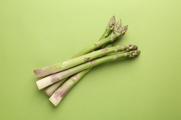 Fresh ripe raw asparagus on green background, top view