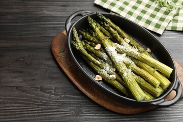 Tasty cooked asparagus served with parmesan on black wooden table, above view. Space for text