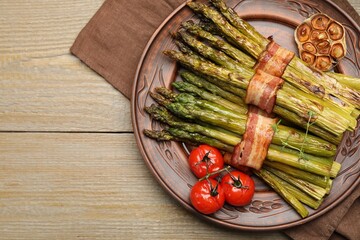 Tasty cooked asparagus served with bacon and spices on wooden table, top view. Space for text