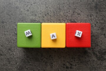 Word Maximum and colorful cubes on grey table, flat lay