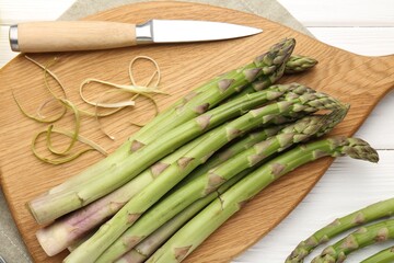 Fresh raw asparagus spears and knife on white wooden table, flat lay