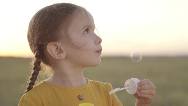 little girl blowing soap bubbles park. happy family. child kid daughter plays game outdoor. baby kid plays soap bubbles nature. children holiday soap bubbles. children blowing ball of soap park.
