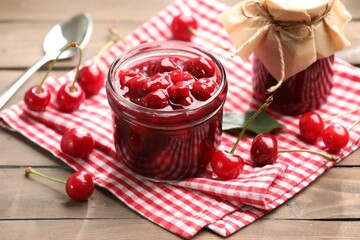 Tasty cherry jam and fresh fruits on wooden table, closeup