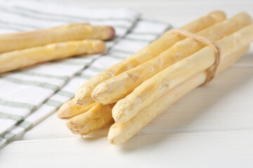 Bunch of raw asparagus spears on white wooden table, closeup