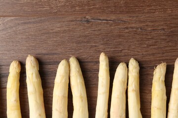 Raw white asparagus spears on wooden table, flat lay. Space for text