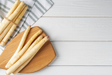 Raw asparagus spears on white wooden table, flat lay. Space for text