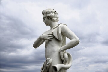 Fototapeta premium Side profile close up of an antique marble statue of the ancient Greek mythological hero Meleager before a dramatic cloudy sky