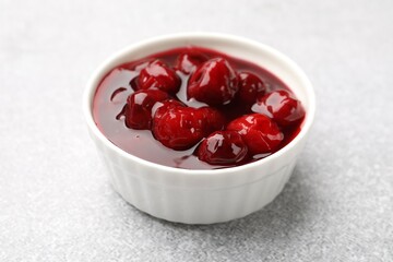 Tasty cherry jam on light table, closeup