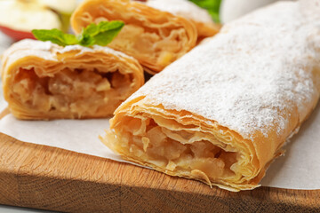 Tasty apple strudels with powdered sugar and mint on table, closeup