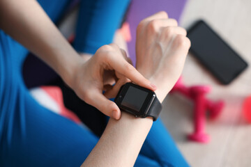 Woman checking fitness tracker during training indoors, closeup