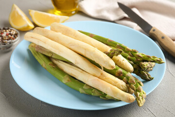 Different raw asparagus spears and spices on grey table, closeup