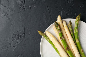 Green and white asparagus on black table, top view. Space for text