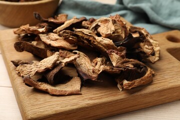 Pieces of dried mushrooms on light wooden table, closeup