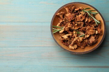 Dried chanterelle mushrooms with rosemary on blue wooden table, top view. Space for text