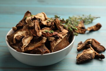 Dried chanterelle mushrooms with thyme on blue wooden table, closeup