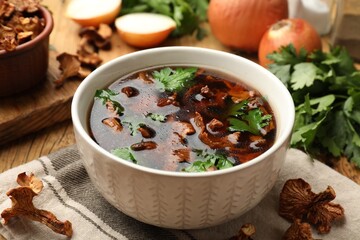 Tasty soup with mushrooms and parsley in bowl on wooden table, closeup