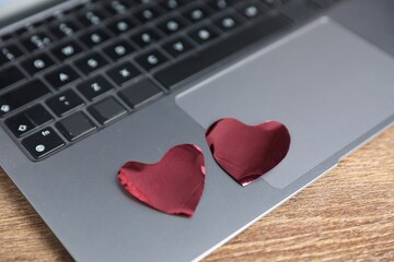 Decorative hearts and laptop on wooden table, closeup. Online dating site