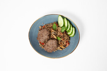 Steamed beef cutlets with buckwheat, sautéed mushrooms, and fresh cucumber slices, served on a plate against a white background