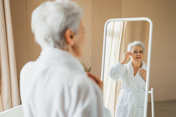 Love yourself. Beautiful old woman enjoying mirror reflection. Senior older lady spending morning...