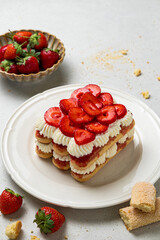 Tradition Italian layered dessert tiramisu with mascarpone cream and ladyfingers biscuits on a white background. Strawberry tiramisu cake. Summer easy no bake dessert. Home cooking. Selective focus.