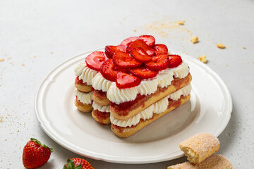 Tradition Italian layered dessert tiramisu with mascarpone cream and ladyfingers biscuits on a white background. Strawberry tiramisu cake. Summer easy no bake dessert. Home cooking. Selective focus.
