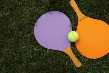 Beach tennis paddles and ball on grass. Active lifestyle, games and sports. Tennis set for the open...