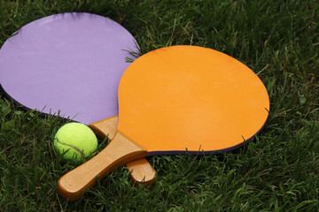 Beach tennis paddles and ball on grass. Active lifestyle, games and sports. Tennis set for the open...