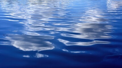 Naklejka premium The tranquil reflections of clouds on a serene blue water surface.