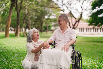 Elderly Asian couple enjoys happy retirement moment park support wheelchair