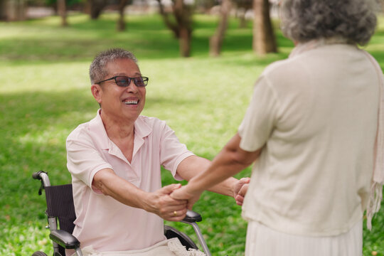 Asian older couple holding hands in park showcasing happy retirement life mutual support emotional wellbeing and enduring relationship bond