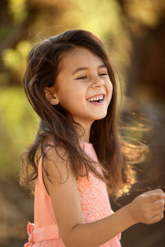 Summer portrait of laughing little girl in nature scene at sunset time, childhood memories and family vacation concept